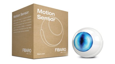 The white Fibaro motion sensor glows blue and lies on a white background with a box.